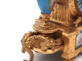 a gold clock with a blue vase on top of it