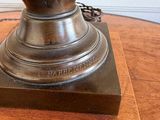a bronze vase sitting on top of a wooden table