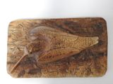 carvings of a bird on a wooden board on a white surface