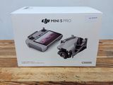 Drone DJI Mini Mini avec son coffret d'accessoires posé sur une table en bois