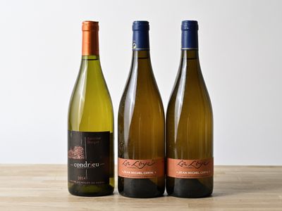 three bottles of wine are lined up on a wooden table