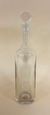 une petite bouteille en verre avec un bouchon transparent, posée sur une table