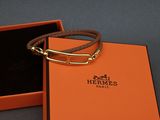 an orange box with a brown leather bracelet inside of it