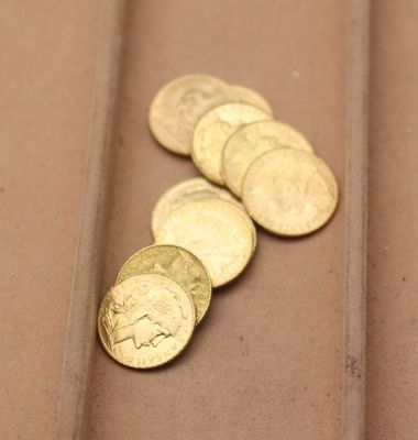 plusieurs pièces d'or posées sur une table marron, à côté d'une paire de ciseaux