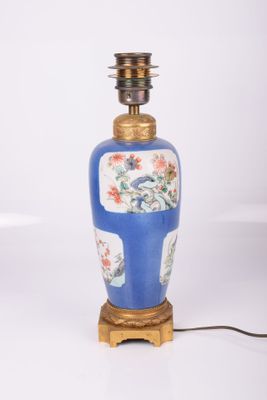 a blue and white vase with a gold base and a light on it