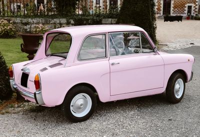 a pink car that is parked on the side of the road