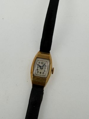 a gold wrist watch with a black band on a white surface