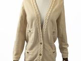 cardigan beige à mailles torsadées sur un mannequin de boutique