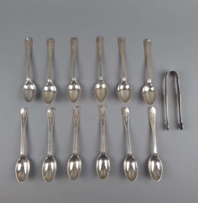 six cuillères en argent et un repose-cuillère posés sur une table