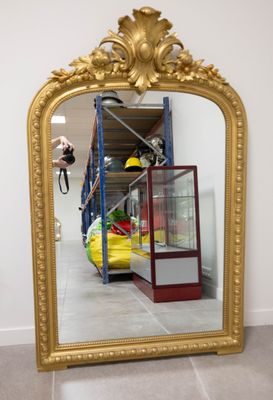 un grand miroir avec un cadre doré dans une pièce