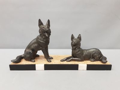 a pair of bronze dog figurines on a wooden base