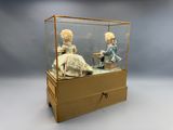 deux poupées dans une vitrine posée sur une table