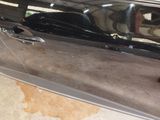 a black car parked in a garage with a brown spot on the floor