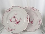 deux assiettes ornées de motifs rouges et blancs, posées sur une surface blanche