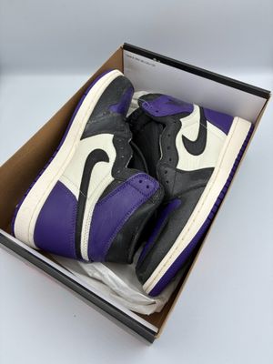 purple and black air jordan 1s in a box on a white surface