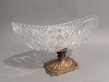 un bol en verre posé sur un socle doré, sur une surface blanche
