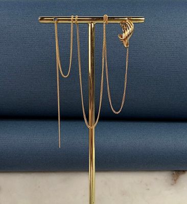 un gros plan d'un présentoir à bijoux plaqué or posé sur une surface en marbre