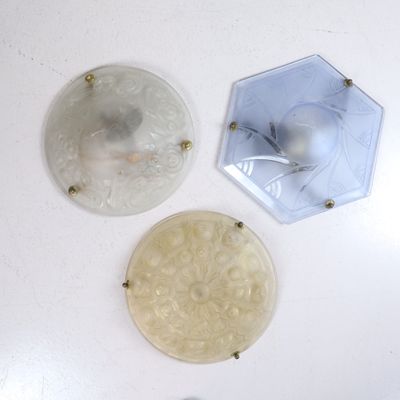 trois assiettes en verre posées sur une table blanche, éclairées par une lampe