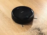 a close up of a black robot on a wooden floor