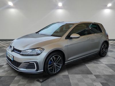 Une Volkswagen Golf argentée est garée dans une pièce au sol carrelé en damier.