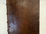 un vieux livre en cuir marron posé sur une table blanche