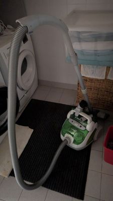un aspirateur posé par terre à côté d'une machine à laver