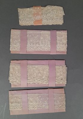 trois morceaux de dentelle rose et blanche posés sur une surface grise