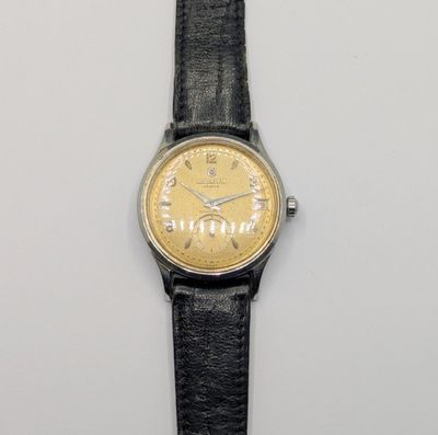 une photo d'une montre-bracelet avec un cadran doré et un bracelet en cuir noir