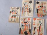 several playing cards are arranged on a blue surface with a clock in the background