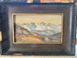 une peinture à l'huile représentant un paysage de montagne, encadrée dans un cadre en bois et posée sur une table