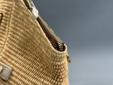 la fermeture éclair d'un sac en paille est ouverte sur un fond gris