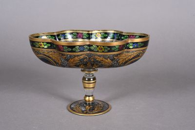 a close up of a metal bowl on a stand with flowers on it