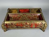 un coffret en verre or et rouge richement décoré, posé sur une surface blanche