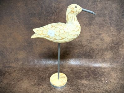 a bird that is standing on a stand on a brown surface