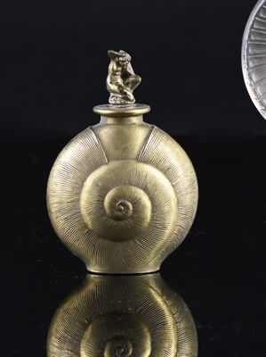 a small gold object on a black surface next to a coin