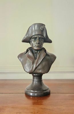 statue représentant le buste d'un homme coiffé d'un chapeau, posée sur une table en bois