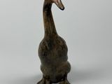 une petite statue représentant un canard posée sur une surface blanche