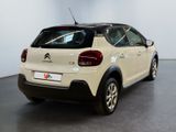 the rear of a white car is parked in a large room