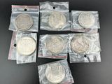six pièces d'argent dans des sachets en plastique posées sur une surface noire