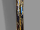 a gold and black sword on display against a gray wall