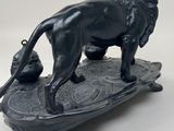 statue of a lion on a skateboard with a ball in its mouth