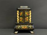 une horloge noire et dorée sur laquelle sont peintes des fleurs