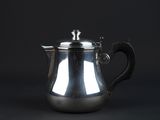 a silver coffee pot with a handle on a black background