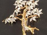 a gold tree brooch with clear stones on it
