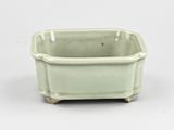 a small green pot with a handle on a white surface