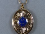 an image of a gold medal with a blue stone in the center