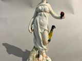 une figurine représentant une femme tenant un oiseau et une fleur