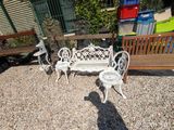 a white bench and two chairs in a gravel area
