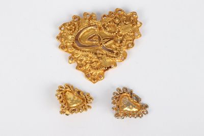 two gold brooches and a pair of earrings on a white surface