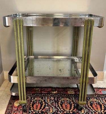 un chariot de bar en chrome et en verre posé sur un tapis dans une pièce